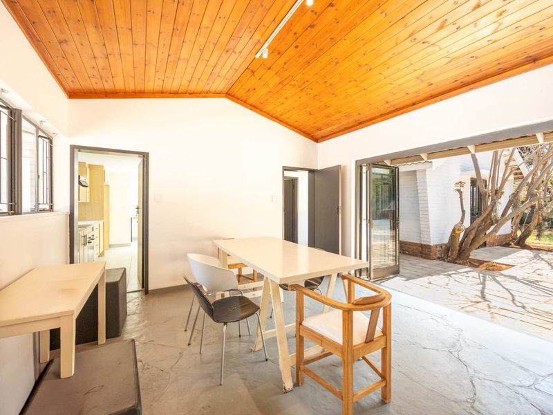 Open-plan living area featuring a vaulted timber ceiling, stone flooring, and bi-fold doors providing seamless access to the outdoor patio area.