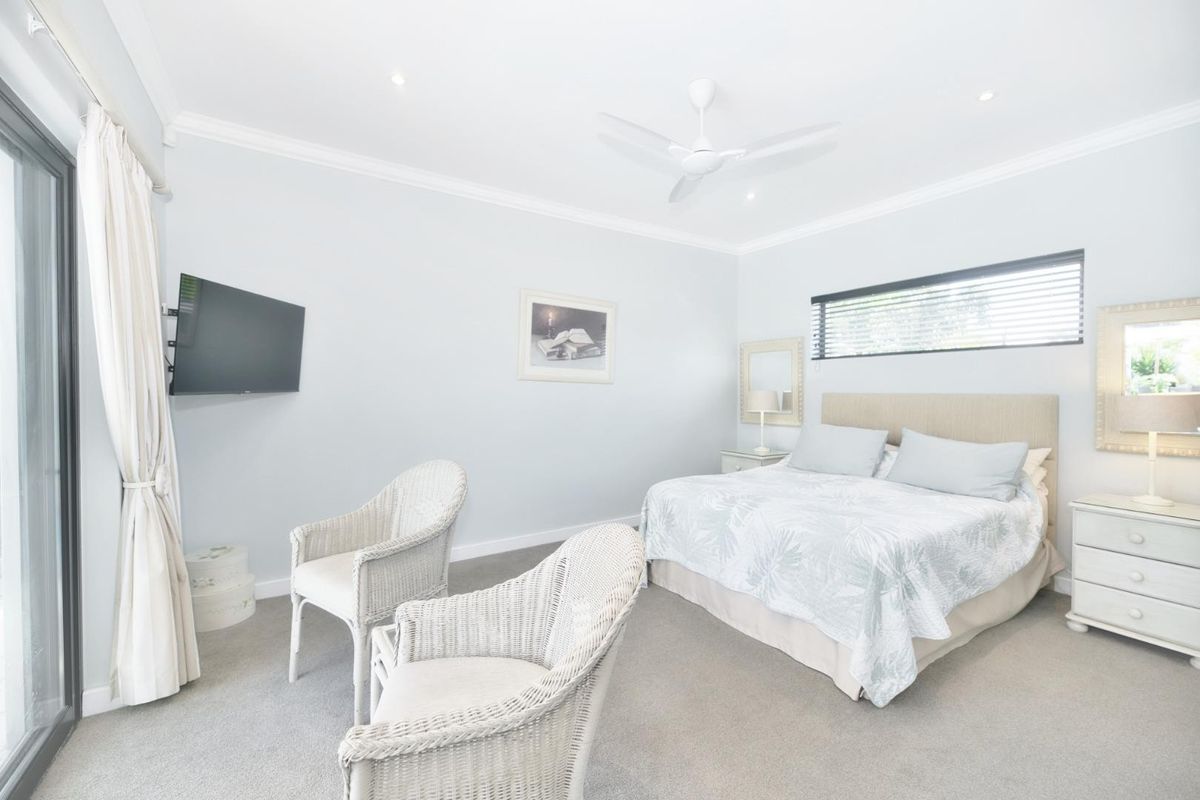 A bright and well-maintained bedroom featuring neutral carpet, recessed lighting, a ceiling fan, and sliding glass doors providing access to the exterior.