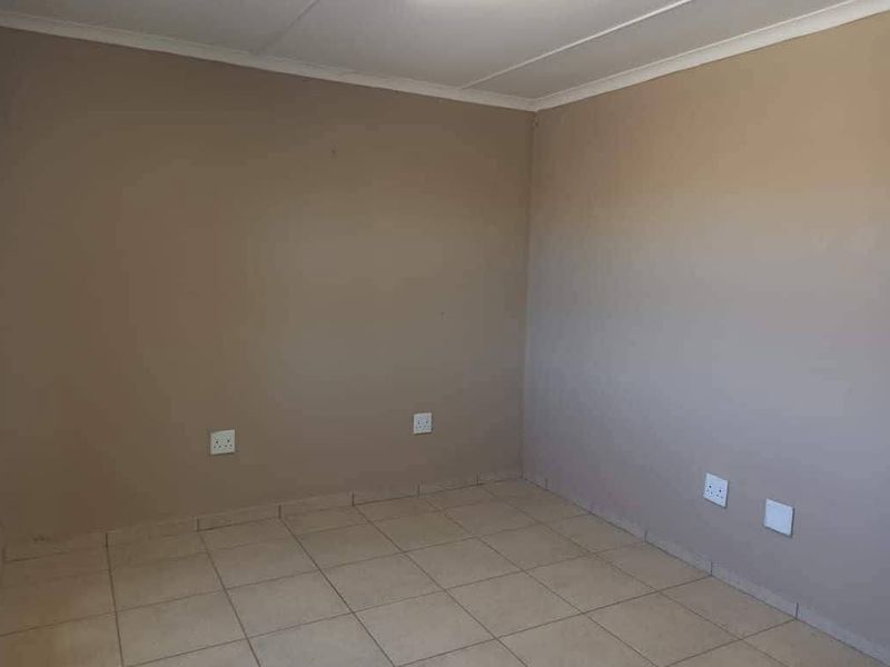 An empty bedroom featuring neutral painted walls, tiled flooring, and multiple electrical power outlets.