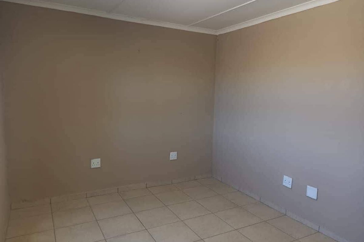 An empty bedroom featuring neutral painted walls, tiled flooring, and multiple electrical power outlets.