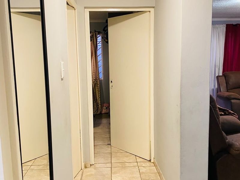A functional hallway featuring tiled flooring and neutral wall finishes, providing access to adjacent rooms within the apartment.