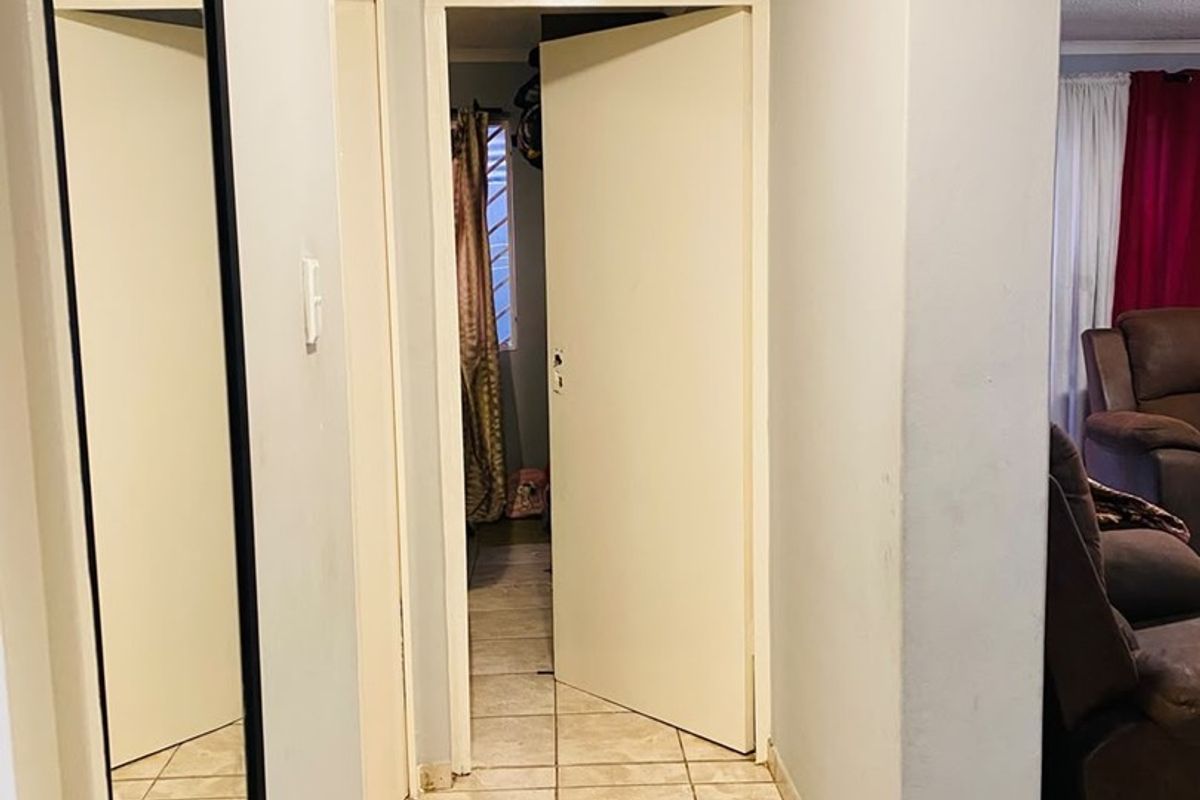 A functional hallway featuring tiled flooring and neutral wall finishes, providing access to adjacent rooms within the apartment.