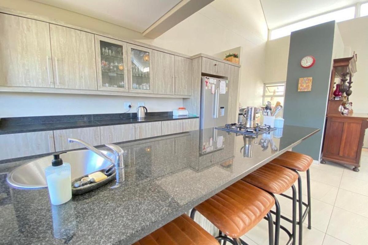 Modern kitchen featuring a large granite-topped island, built-in cabinetry, and high vaulted ceilings with clerestory windows for natural light.