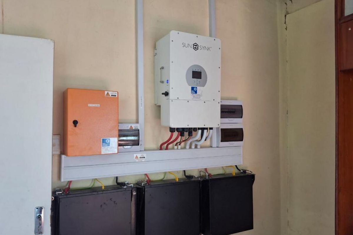 Utility area featuring a wall-mounted solar inverter and battery storage system with associated electrical distribution boards.