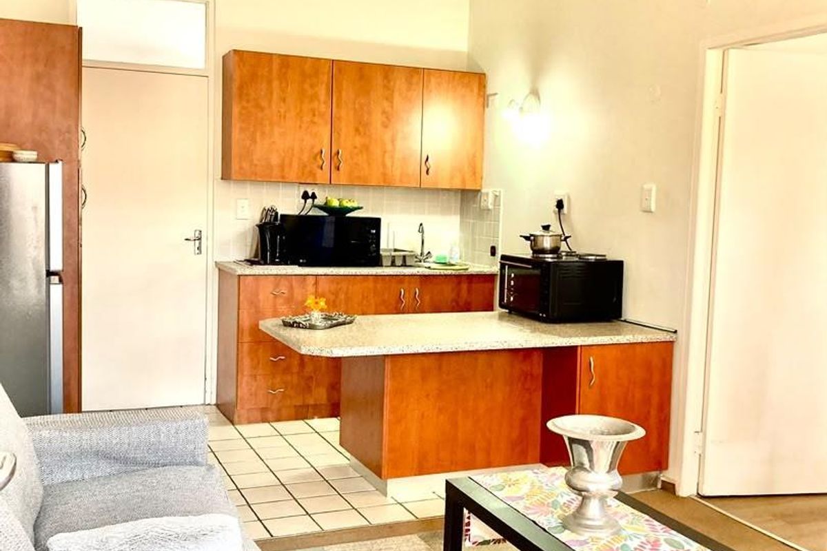 Open plan living area featuring a functional kitchen with laminate cabinetry, tiled flooring, and a breakfast counter, suitable for comfortable retirement living.