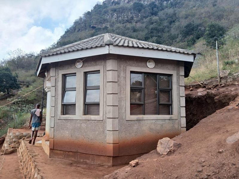 A detached structure with a tiled roof and aluminium windows, situated on a sloped site with visible earthworks and unfinished exterior wall finishes.