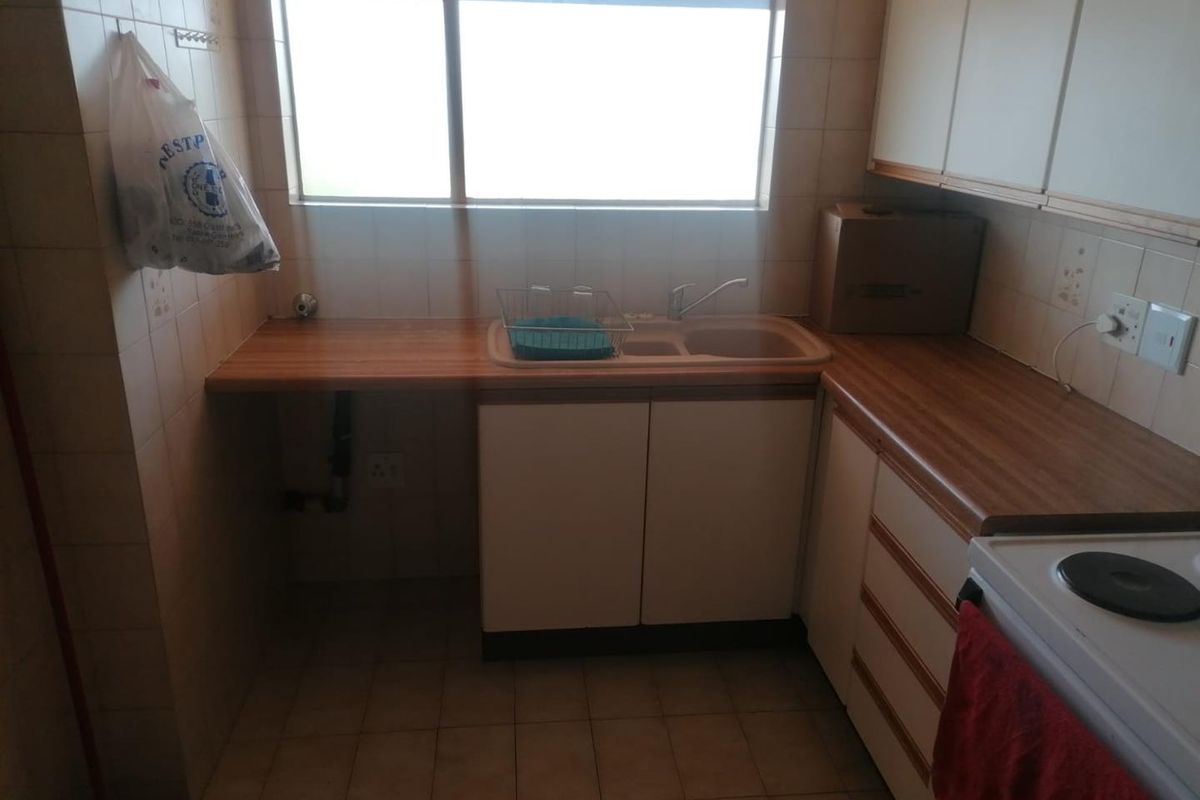 A functional kitchen featuring laminate countertops, a double basin sink, and built-in cabinetry with a tiled backsplash and floor.