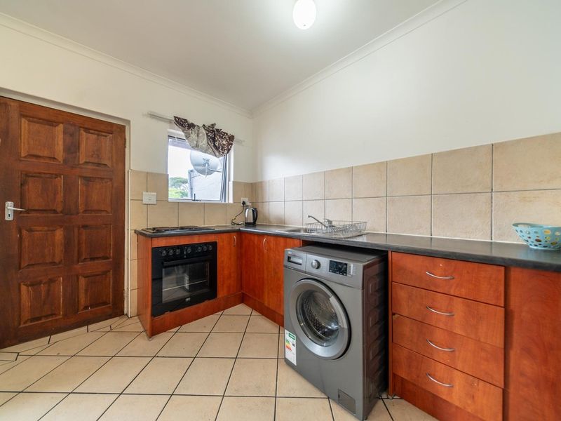 A functional kitchen featuring wooden cabinetry, laminate countertops, a built-in oven, hob, and tiled finishes, providing a practical workspace.