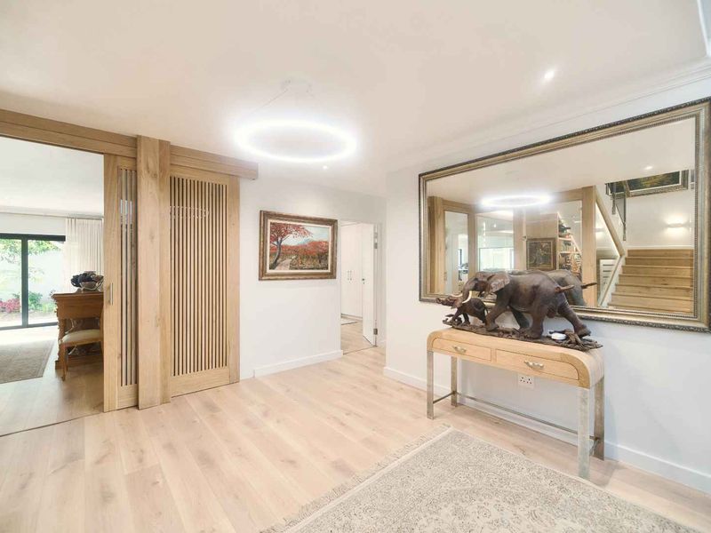 A bright and modern entrance hall featuring light timber flooring, elegant sliding doors, and a staircase leading to the upper level.