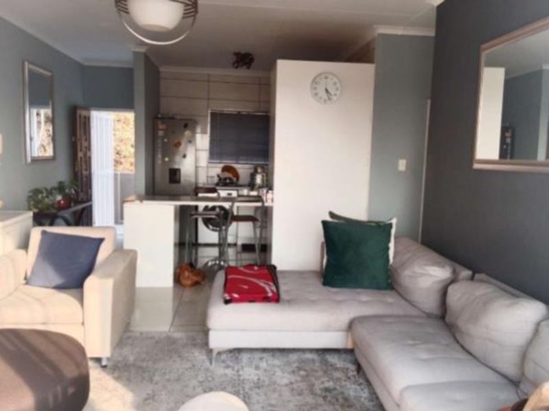 Open-plan living area featuring a kitchen with a breakfast island and tiled backsplash, seamlessly connected to the lounge space.