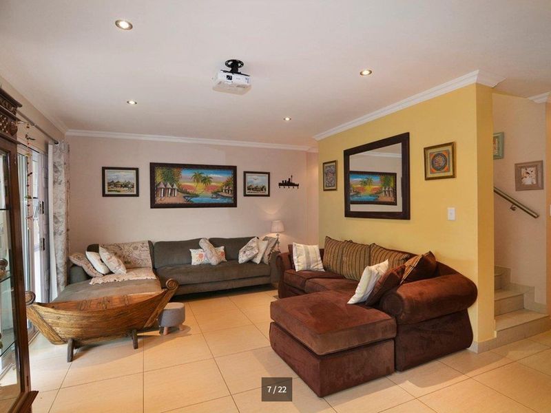 Spacious living room featuring tiled flooring, recessed lighting, a ceiling-mounted projector, and direct access to an outdoor area via sliding glass doors.