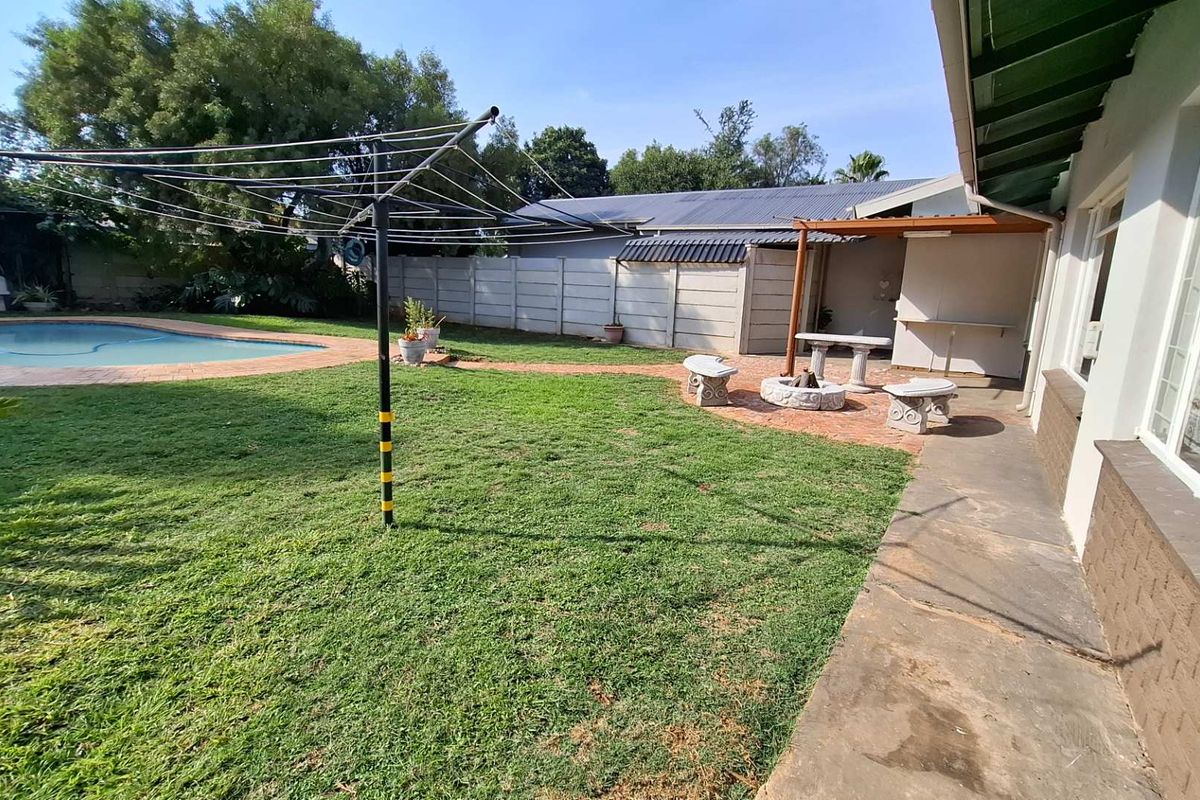 Rear garden featuring a swimming pool, brick-paved patio area with a pergola, and perimeter precast concrete walling.