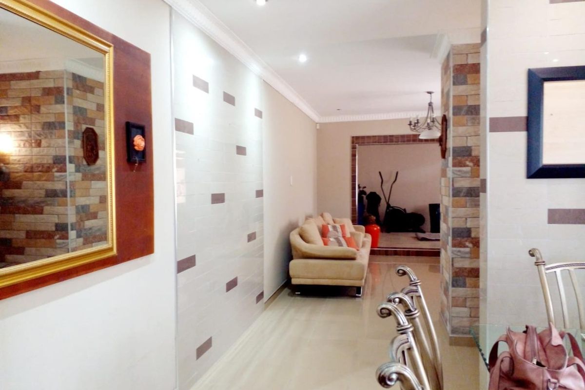 Spacious living area featuring decorative stone veneer wall accents, recessed lighting, crown molding, and polished tile flooring throughout.