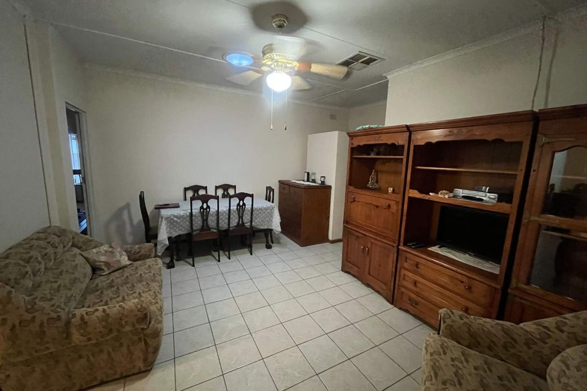 A functional living and dining area featuring tiled flooring, a central ceiling fan, and neutral wall finishes.