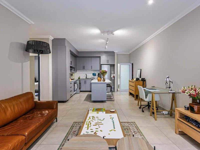 Spacious open-plan living area featuring a modern kitchen with grey cabinetry, a central island, and neutral tiled flooring throughout.