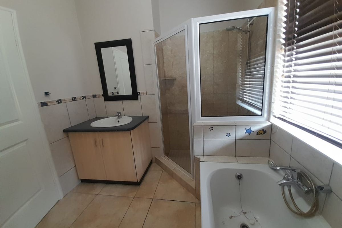 A functional bathroom featuring a vanity cabinet, a separate glass-enclosed shower, and a bathtub with a handheld shower attachment.
