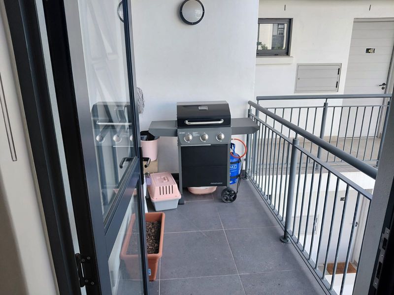 A functional balcony space featuring tiled flooring and a secure metal balustrade, providing a compact outdoor area accessible from the main living space.