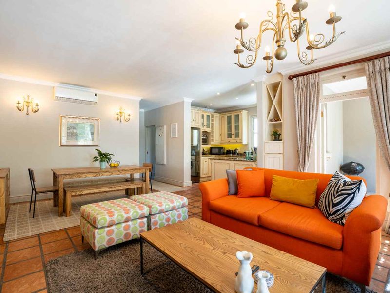 Spacious open-plan living and dining area featuring terracotta flooring, integrated kitchen cabinetry, and direct access to an outdoor patio space.
