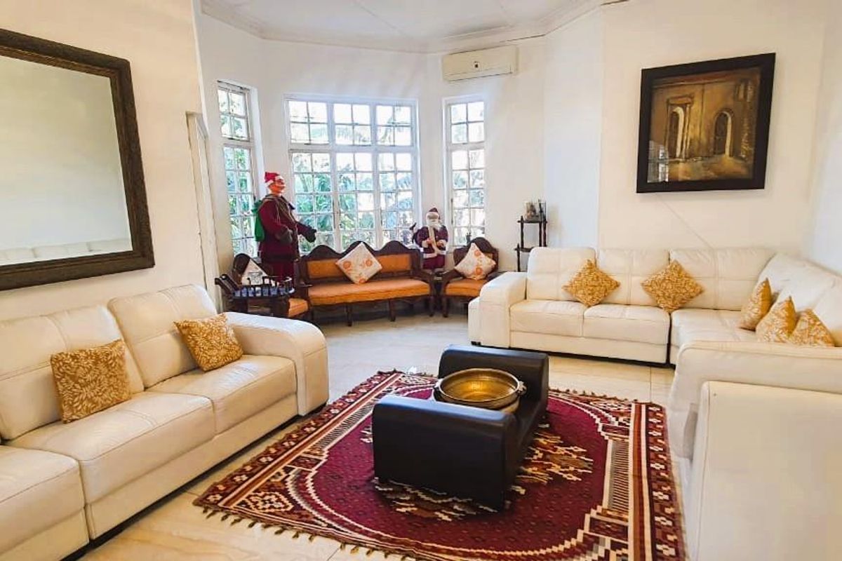 Spacious living room featuring large bay windows, tiled flooring, and a wall-mounted air conditioning unit, offering a bright and comfortable living space.