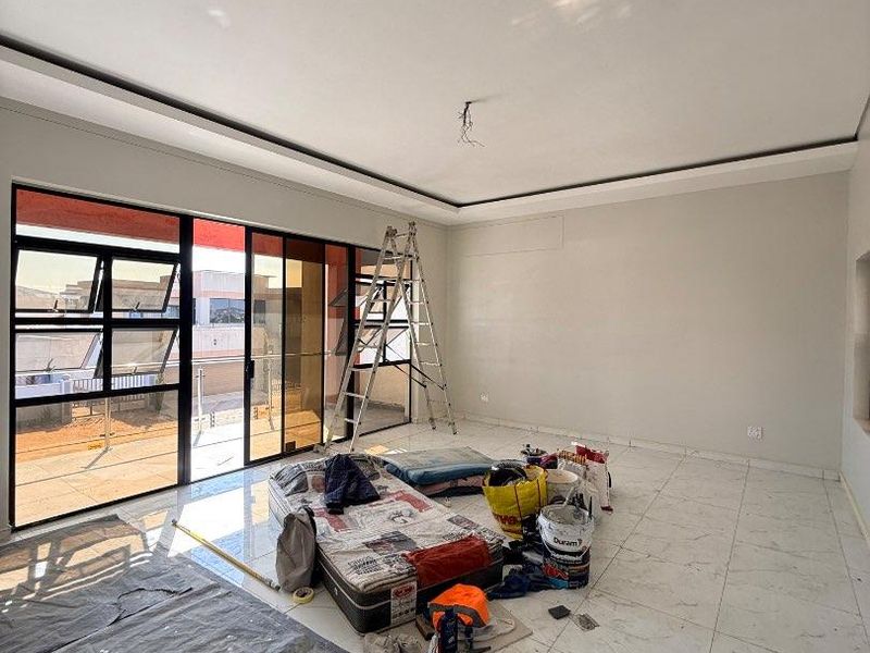 Spacious living area featuring large format floor tiles, recessed ceiling detail, and sliding glass doors leading to an outdoor balcony.
