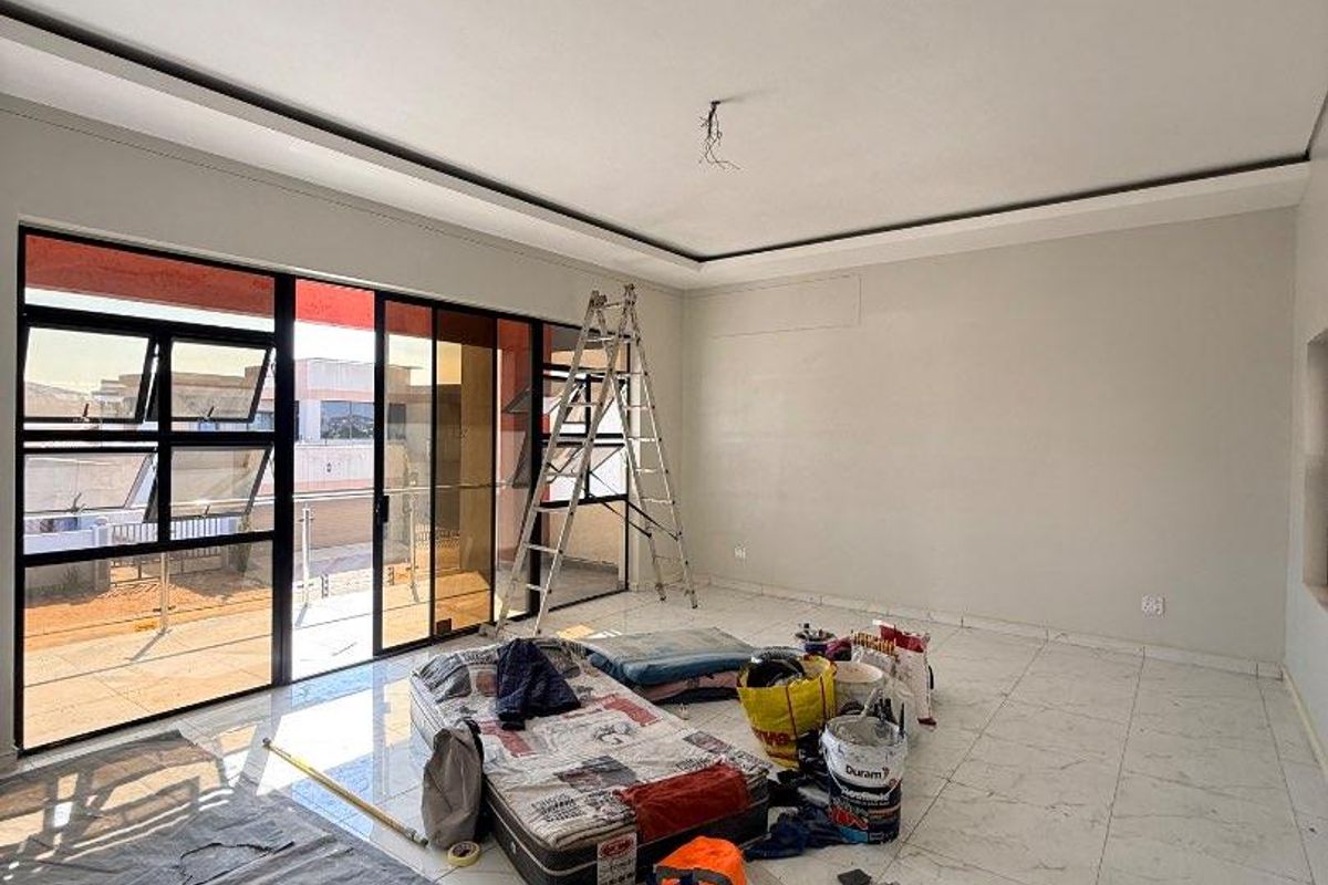 Spacious living area featuring large format floor tiles, recessed ceiling detail, and sliding glass doors leading to an outdoor balcony.