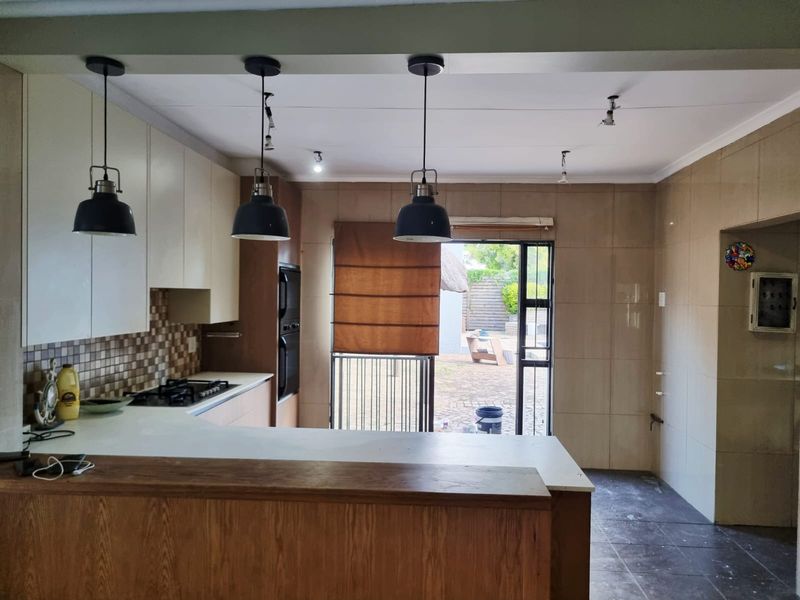 Modern kitchen featuring built-in cabinetry, gas hob, oven, and a breakfast bar, with direct access to the rear patio area.