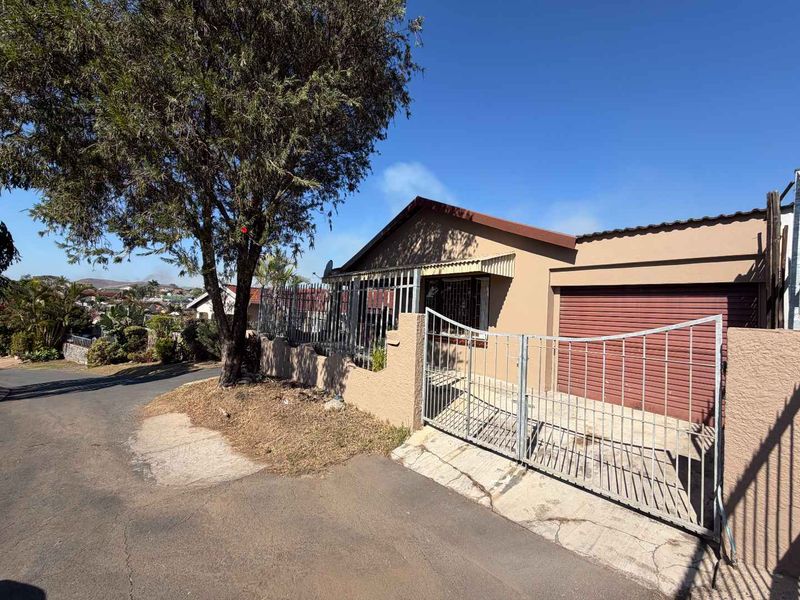 Front exterior view of a residential property featuring a metal security gate, perimeter fencing, and a roller garage door.