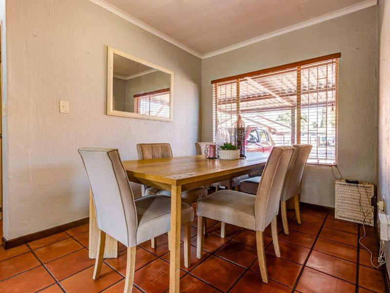 A dining room featuring terracotta floor tiles, cove cornicing, and wooden window blinds, providing a functional space for family meals.