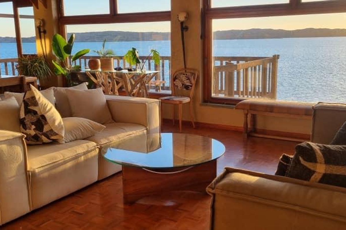 Spacious living area featuring expansive windows with panoramic water views, parquet flooring, and direct access to an outdoor balcony.