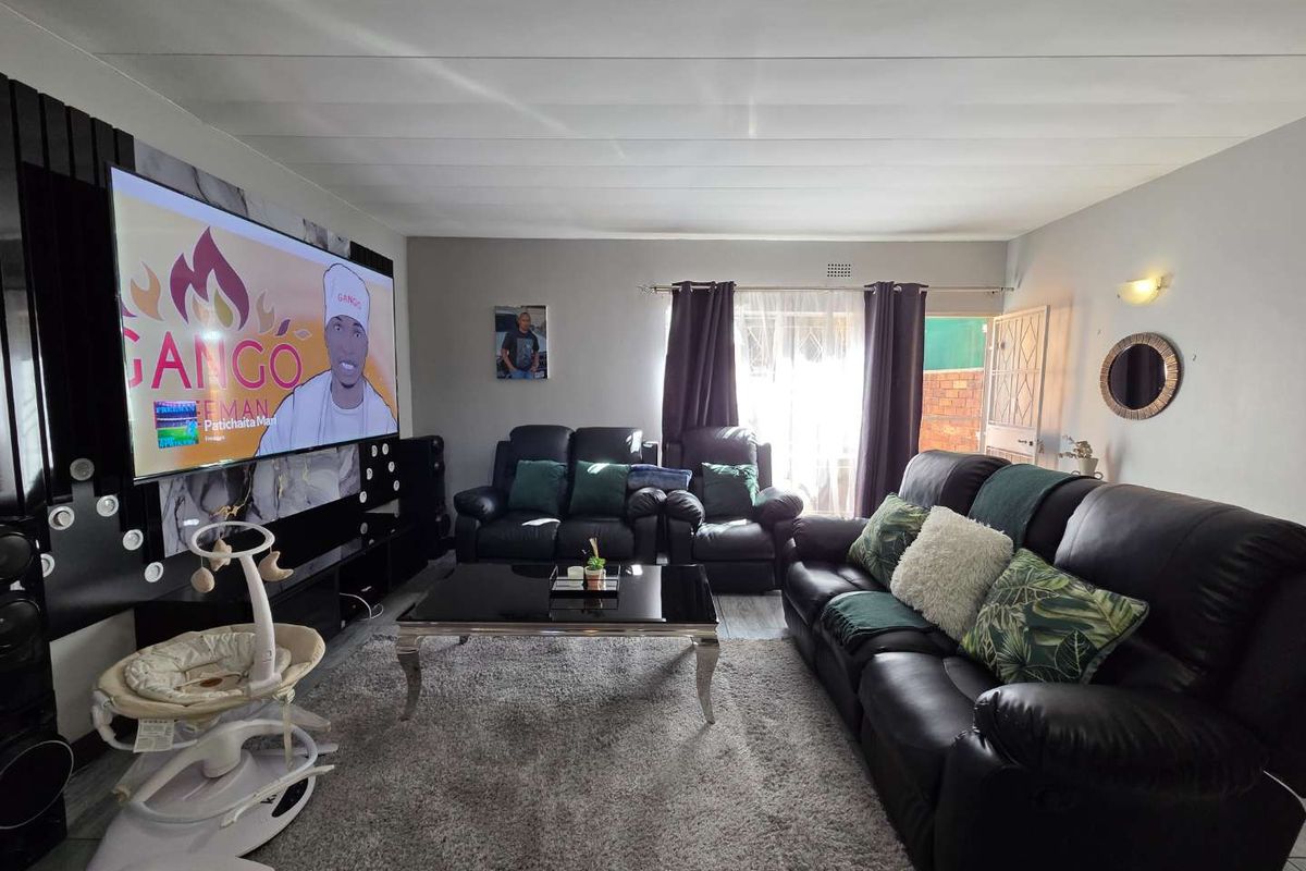A comfortable living room featuring a large wall-mounted entertainment unit and direct access to an outdoor area through a glass door.