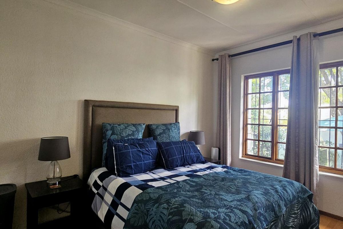 A well-lit bedroom featuring wooden-framed windows, neutral walls, and classic cornicing, providing a comfortable and functional living space.