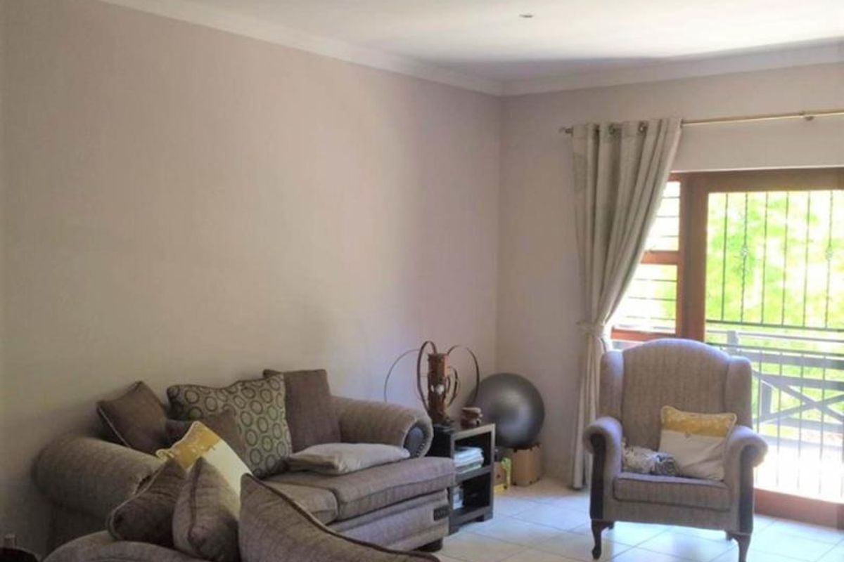A comfortable living room featuring tiled flooring, recessed lighting, and a sliding glass door with security gate providing access to the outdoors.