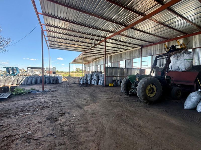 A large, open-sided agricultural utility shed with a corrugated metal roof and steel frame, suitable for storage or farm equipment housing.