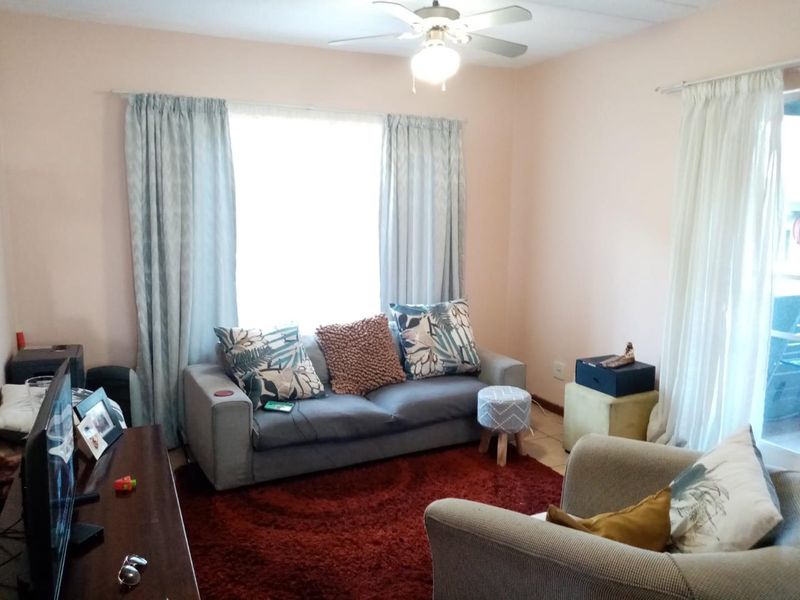A comfortable living room featuring a ceiling fan, tiled flooring, and a sliding glass door providing natural light.
