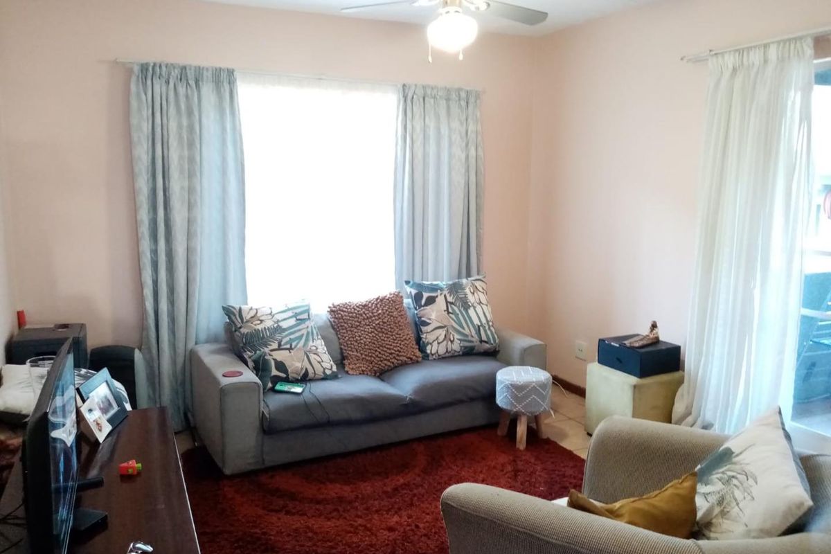 A comfortable living room featuring a ceiling fan, tiled flooring, and a sliding glass door providing natural light.