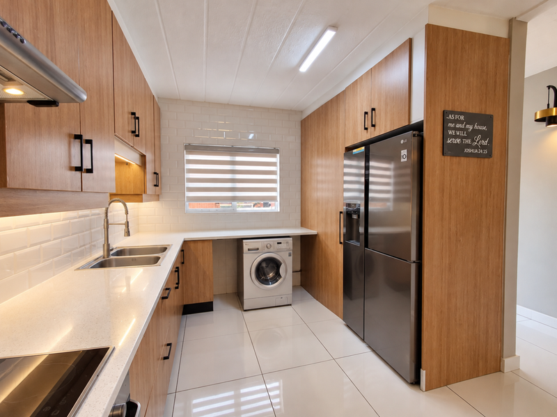 Modern kitchen featuring wood-look cabinetry, quartz countertops, subway tile backsplash, and integrated appliances with clean, contemporary finishes.