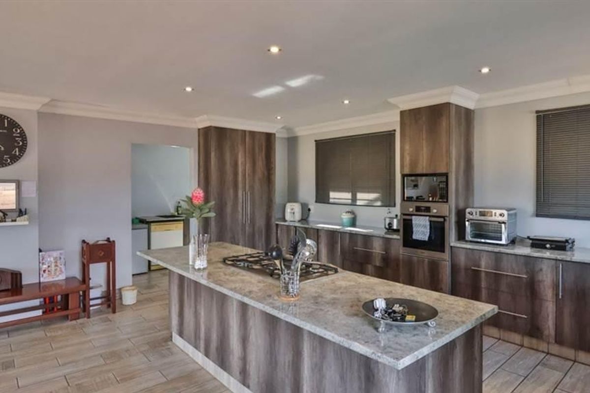 Modern kitchen featuring a central island with a gas cooktop, stone countertops, built-in oven, and ample cabinetry, complemented by tiled flooring and recessed lighting.