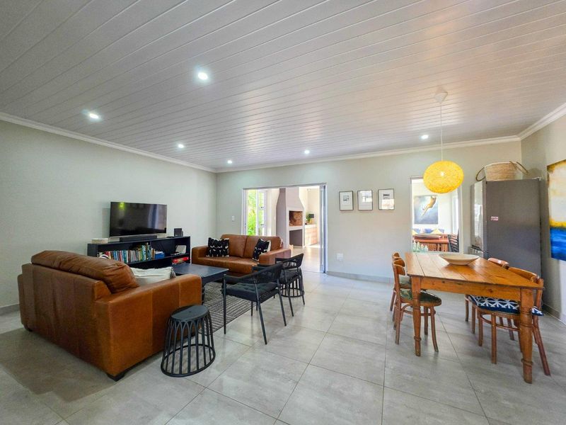 Spacious open-plan living and dining area featuring tiled floors, recessed lighting, and a tongue and groove ceiling, with direct access to an outdoor patio.