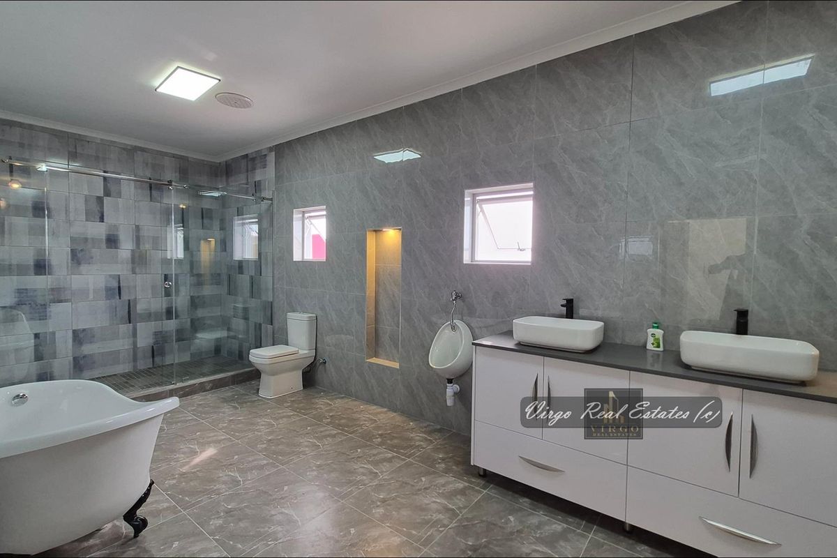 Modern, spacious bathroom featuring a freestanding bathtub, glass-enclosed shower, double vanity, and contemporary grey marble-look tiling throughout.