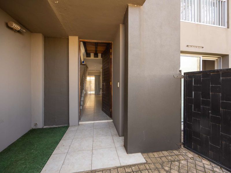 A private entrance area featuring tiled flooring, a timber front door, and a metal security gate, leading into the main living space.