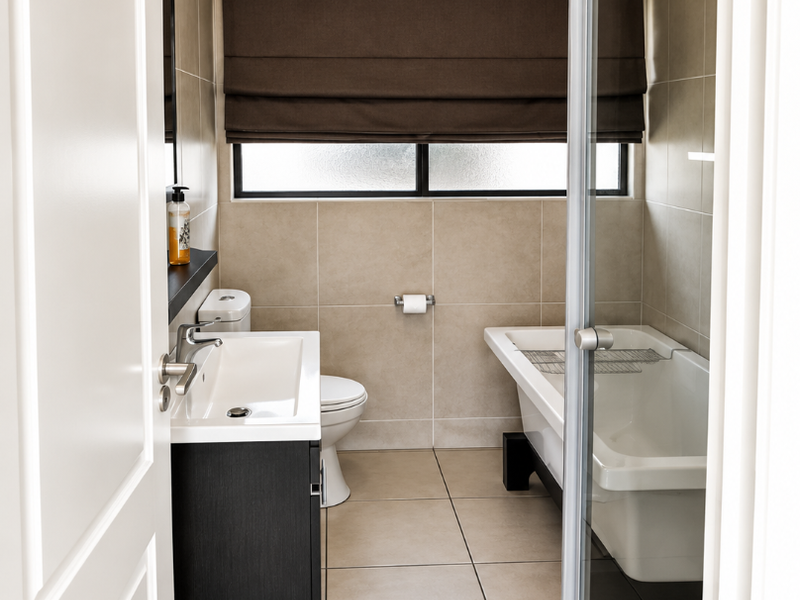 Modern bathroom featuring a wall-mounted vanity, integrated basin, freestanding bathtub, and a separate glass-enclosed shower with neutral floor-to-ceiling tiling.