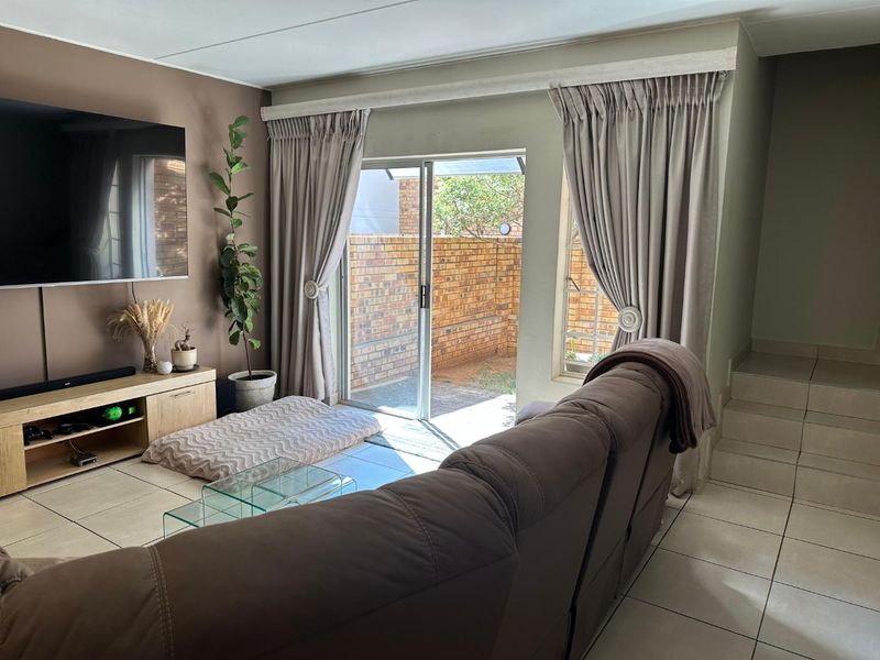 A comfortable living room featuring tiled flooring, a staircase, and a sliding glass door that provides direct access to the rear patio area.