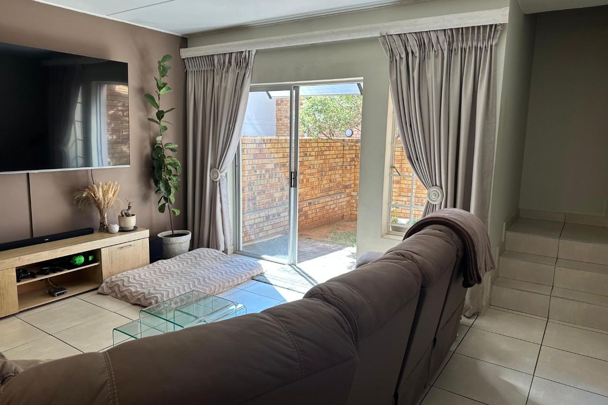 A comfortable living room featuring tiled flooring, a staircase, and a sliding glass door that provides direct access to the rear patio area.