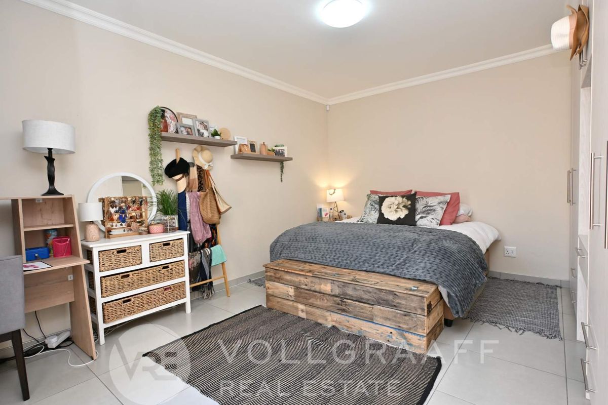 A well-maintained bedroom featuring neutral wall tones, tiled flooring, crown molding, and built-in wardrobe storage.