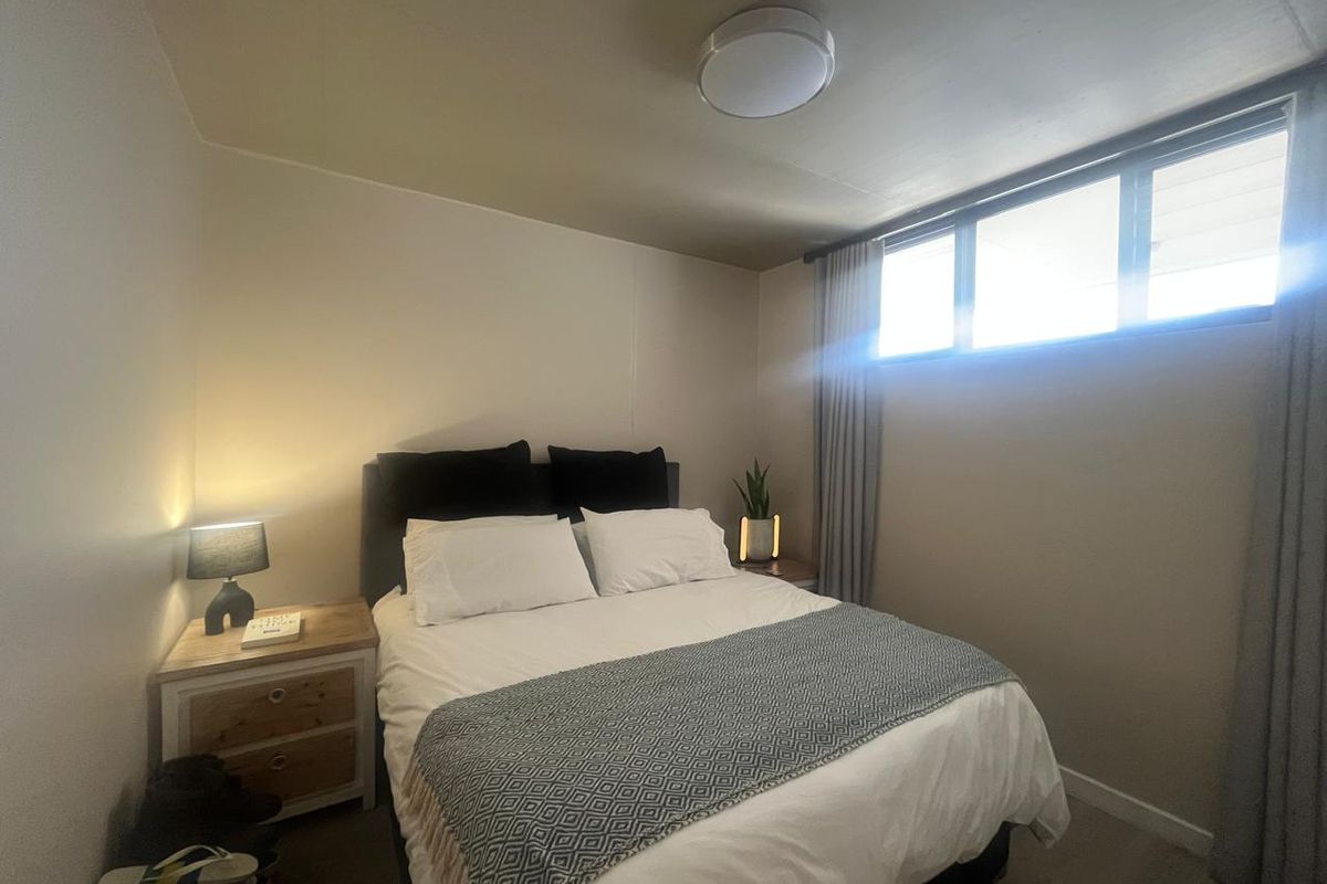 A functional bedroom featuring a horizontal sliding window with curtain tracks and a central ceiling light fixture.