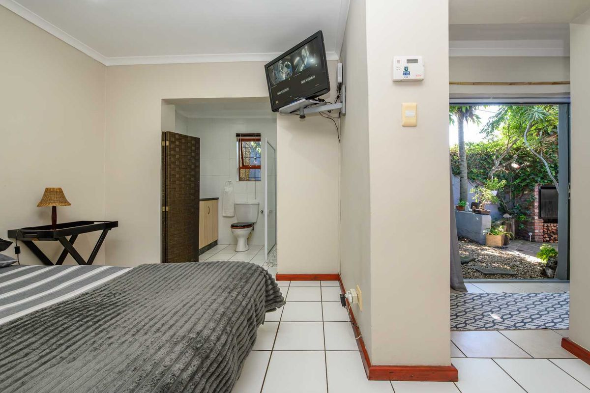Bedroom featuring tiled flooring, an en-suite bathroom, and direct access to a private rear patio area.