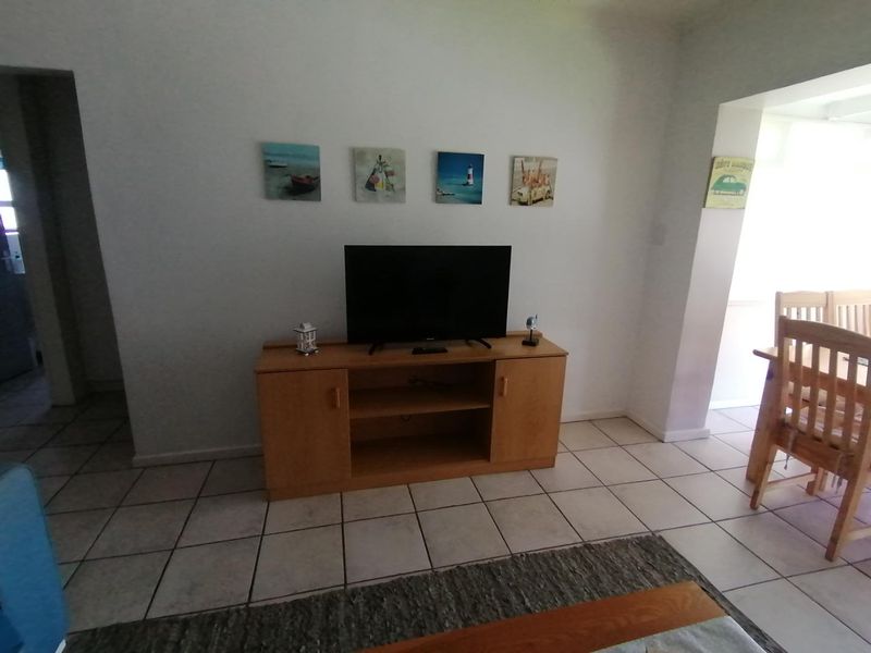 A living area featuring neutral tiled flooring and a clean, open layout connecting to the adjacent dining space.