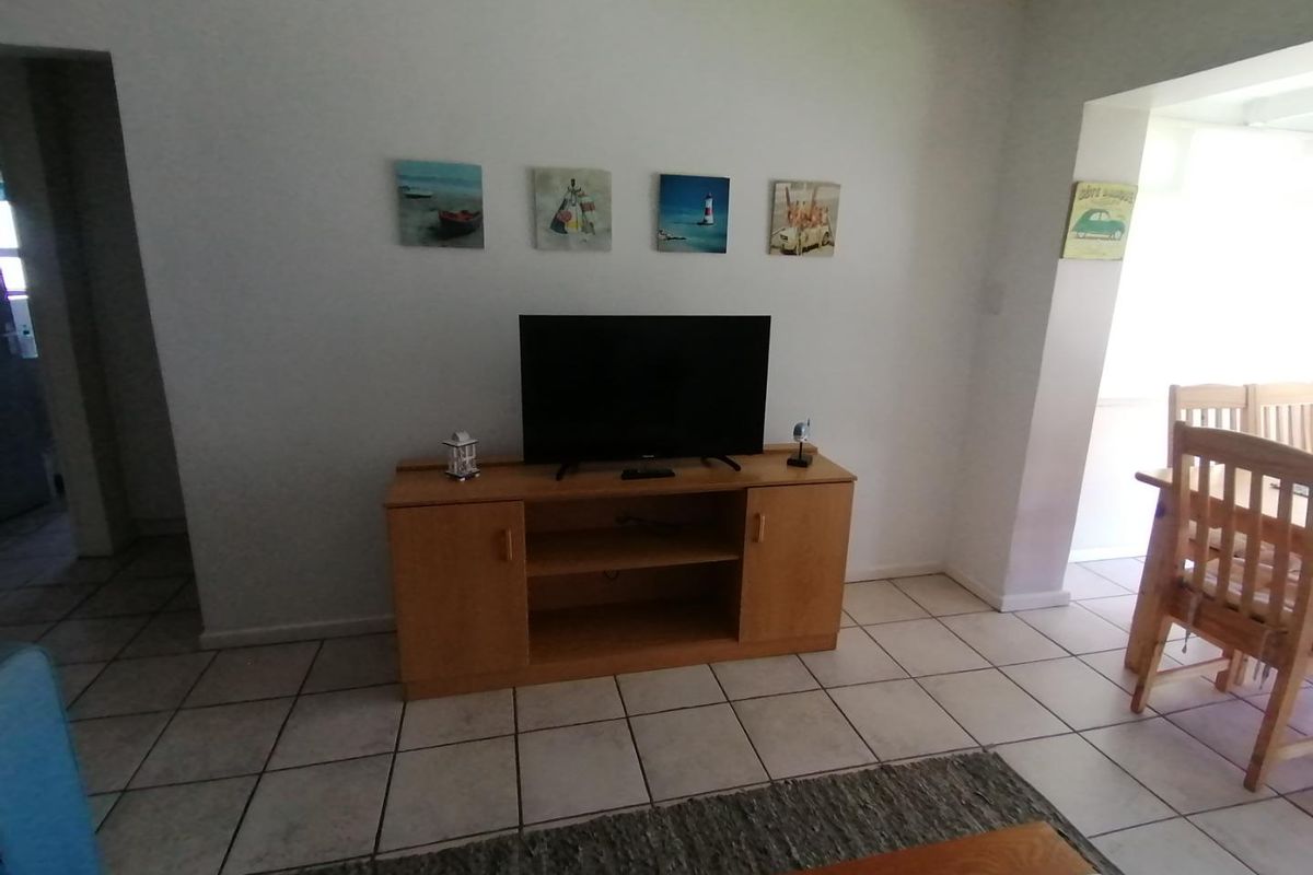 A living area featuring neutral tiled flooring and a clean, open layout connecting to the adjacent dining space.