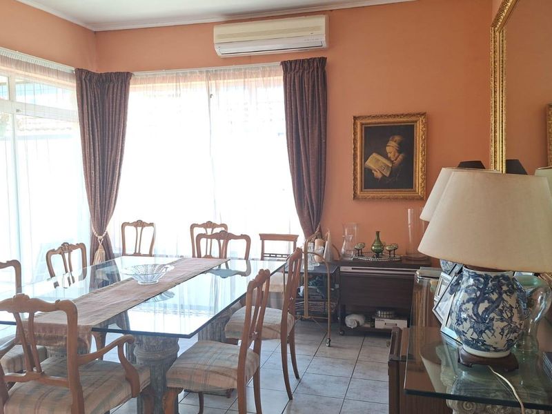 A dining room featuring tiled flooring, a split-system air conditioner, and large sliding glass doors providing natural light.