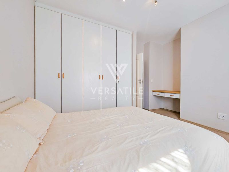 A well-maintained bedroom featuring extensive floor-to-ceiling built-in cupboards and a convenient integrated vanity desk area.
